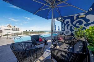 een terras met stoelen en een parasol en een zwembad bij Spacious Studio Rooftop Pool & Bar with Ocean View in Miami Beach