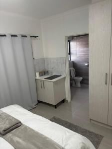 a white bathroom with a sink and a toilet at Oasis in Windhoek