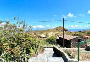 a stone pathway leading to a house with a hill in the background at Encantadora casa rural con altillo in Mocanal +8 photos