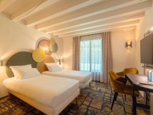 a hotel room with two beds and a desk at Mercure Auxerre Autoroute du Soleil in Appoigny