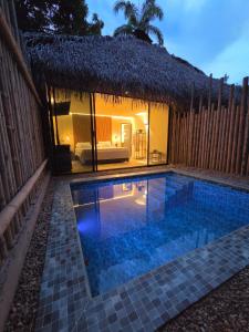 a small swimming pool in front of a hut at Fm Luxury villa Arquitectura tipo yakarta con Playa artificial y Cinema al aire libre in Melgar