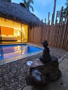 une statue assise sur un rocher à côté d'une piscine dans l'établissement Fm Luxury villa Amalfitana con Playa artificial, pisicna privada, à Melgar