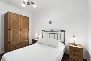 TesbaboにあるApartamento Acogedor en la isla de el Hierroの白いベッドと木製キャビネット付きのベッドルーム1室が備わります。