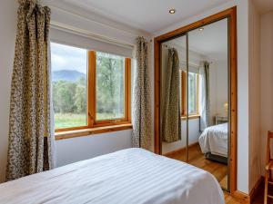 ein Schlafzimmer mit einem Bett und einem großen Fenster in der Unterkunft 4 Bed in Fort William 78875 in Torcastle