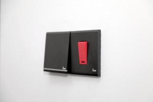 a black switch with a red button on a white wall at Rome NOMADIC Hotel in Negombo