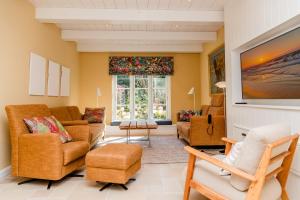 a living room with a couch and chairs and a tv at Hummerklippen a in Süderende