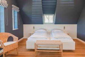 a bedroom with a white bed and a chair at Hummerklippen a in Süderende