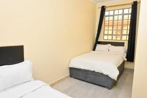 two beds in a room with a window at Two Bedroom Free Wi-Fi and Netflix in Nanyuki on your way to Ol Pejeta Conservancy in Nanyuki