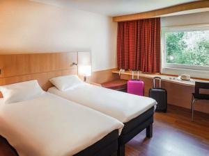 Una habitación de hotel con dos camas y un escritorio. en ibis Belfort Danjoutin, en Belfort 80 fotos más