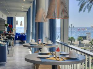 a restaurant with tables and chairs with a view of the ocean at Mercure Nice Promenade Des Anglais in Nice