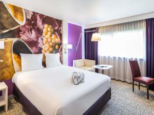 a hotel room with a bed with two wedding shoes on it at Mercure Strasbourg Aéroport in Ostwald