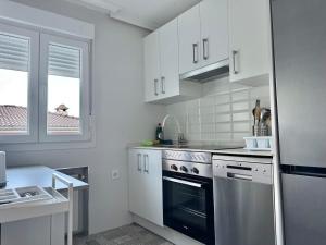a kitchen with white cabinets and a black oven at Casa Rural Madrid Pantano San Juan con Piscina y BBQ in Navahondilla