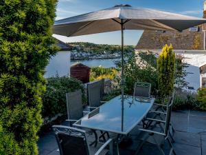 a table and chairs with an umbrella on a patio at 4 Bed in Polruan PC044 in Fowey