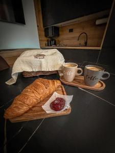 a table with two cups of coffee and a loaf of bread at Apartmán TatraNest in Nová Lesná