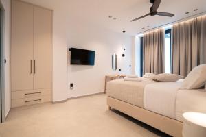 ein weißes Schlafzimmer mit Bett und Flachbildfernseher in der Unterkunft Eleage Villas in Lefkada Town