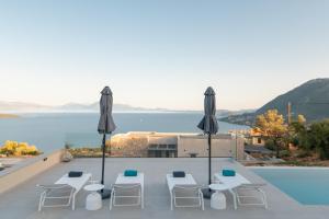 Aussicht vom Dach eines Hauses mit Stühlen und Sonnenschirmen in der Unterkunft Eleage Villas in Lefkada Town