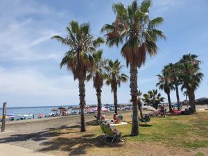 people sitting in lawn chairs under palm trees on the beach at Casa Linda in Almáchar