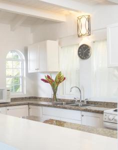 una cucina con lavandino e orologio sul muro di Windjammer Landing Resort and Residences a Gros Islet