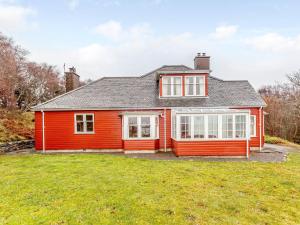 a red house with white windows and a yard at 6 Bed in Lairg CA210 in Achlyness