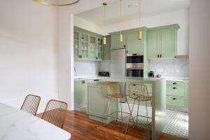 una cucina con armadi verdi e un tavolo con sedie di Boavista Gem Villa a Porto