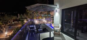 an outdoor table with an umbrella on a balcony at night at Cretan stars villas in Limín Khersonísou