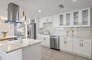 a kitchen with white cabinets and stainless steel appliances at Luxury Coastal Retreat in Largo
