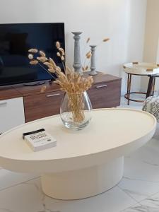 a white coffee table with a vase of flowers on it at CENTRAL SPOT AXD in Alexandroupoli