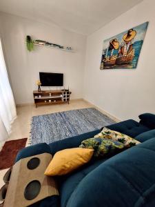 a living room with a blue couch and a television at La casa Azul- Búzios in Búzios