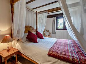 een slaapkamer met een hemelbed met rode kussens bij 1 Bed in Bude WBARN in Sutcombe