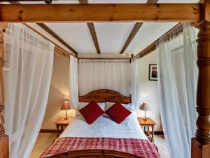 a bedroom with a canopy bed with red pillows at 1 Bed in Bude WBARN in Sutcombe