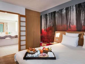 a hotel room with a tray of food on a bed at Novotel Paris Est in Bagnolet