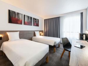 Una habitación de hotel con dos camas y un escritorio. en Novotel Paris Est, en Bagnolet 151 fotos más