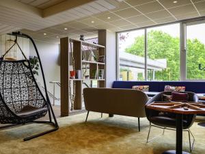 a room with a couch and a table and chairs at Novotel Paris Créteil Le Lac in Créteil