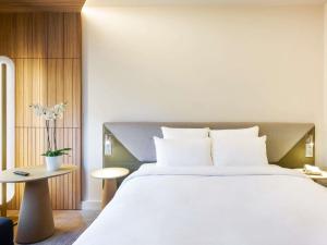 a bedroom with a large white bed and a table at Novotel Marne La Vallée Collégien in Collégien