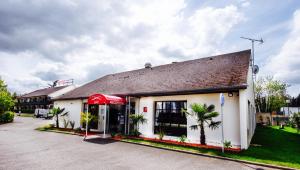 a red gas station with palm trees in front of it at Hotel Pavillon des Gatines in Plaisir