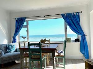 a dining room with a table and a view of the ocean at 3 The Moorings, East Wittering in East Wittering