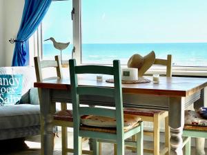 a dining room table with a view of the ocean at 3 The Moorings, East Wittering in East Wittering