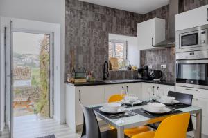 a kitchen with a table and chairs and a kitchen with a window at Casa Pyrrhula Murina - Private Jacuzzi in Nordeste