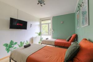 a bedroom with two beds and a tv on the wall at Appartement 2 Chambres - Le Tropical in Oullins