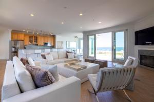 a living room with white furniture and a kitchen at Spectacular 8 Bedroom Oceanfront Hamptons Beach House, Your Castle By The Sea ! in Remsenburg