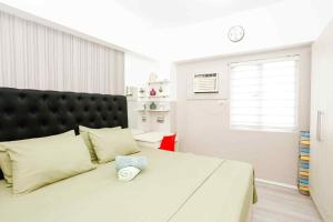 a bedroom with a large white bed with a black headboard at Sky's Cozy Nest in Cebu City +6 photos