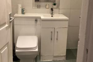 a white bathroom with a sink and a toilet at Sleeps 11 -Pets Ok - Private Garden - Free Parking in Dagenham Dock