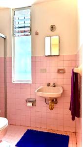 een roze betegelde badkamer met een wastafel en een raam bij Habitación in Morelia