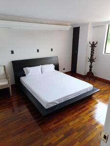Un dormitorio con una cama grande con sábanas blancas. en De vuelta al sol, en Medellín 4 fotos más