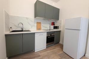 una cucina con armadi grigi e frigorifero bianco di Le Notre-Dame - Grand T3, vue église, centre a Bergerac