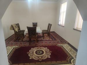 a dining room with a table and chairs on a rug at Уютный и компактный дом in Samarkand