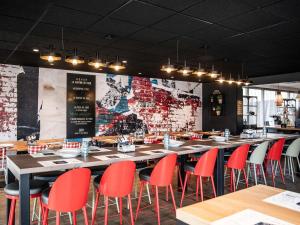 a restaurant with red chairs and tables and a brick wall at Hotel Novotel Evry Courcouronnes in Evry-Courcouronnes