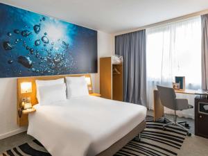 a hotel room with a bed and a desk at Hotel Novotel Evry Courcouronnes in Evry-Courcouronnes