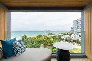 a room with a large window with a couch and a table at Pattaya Marriott Resort and Spa in Jomtien Beach