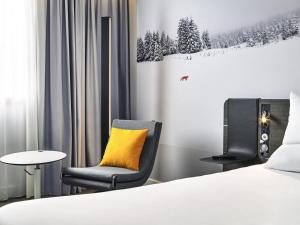 une chambre avec un lit, une chaise et une table dans l'établissement Novotel Antibes Sophia Antipolis, à Valbonne